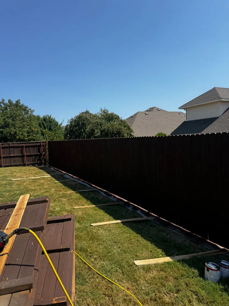 Long dark-stained privacy fence along a backyard