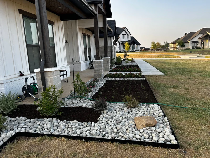 Long finished front-yard planting beds with river-rock walkways