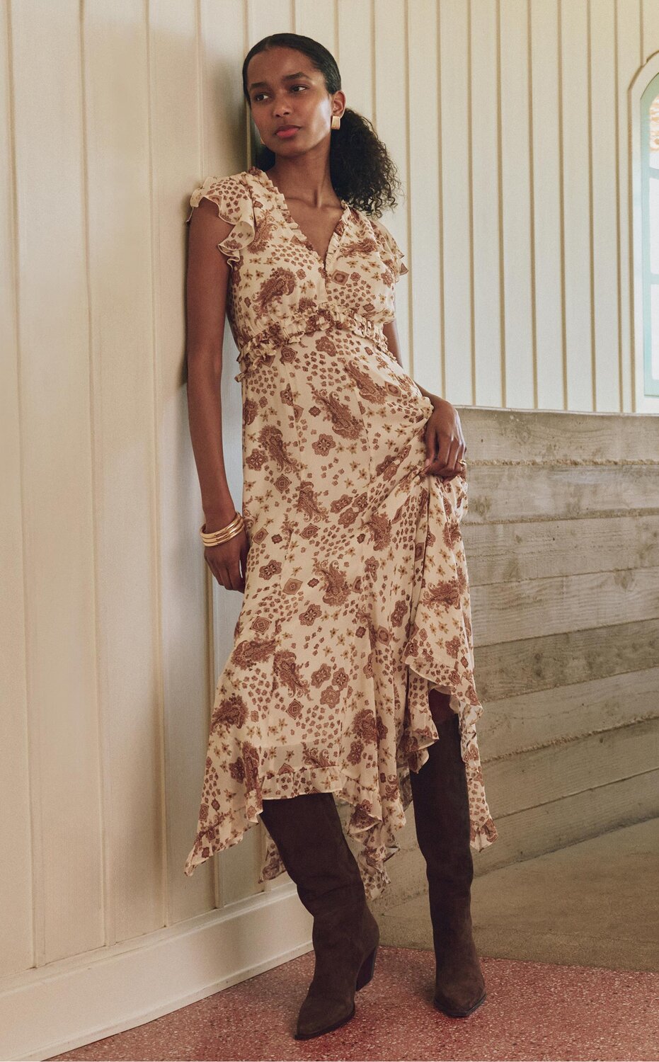 Woman wearing a cream and brown paisley printed mini dress and tall brown suede boots