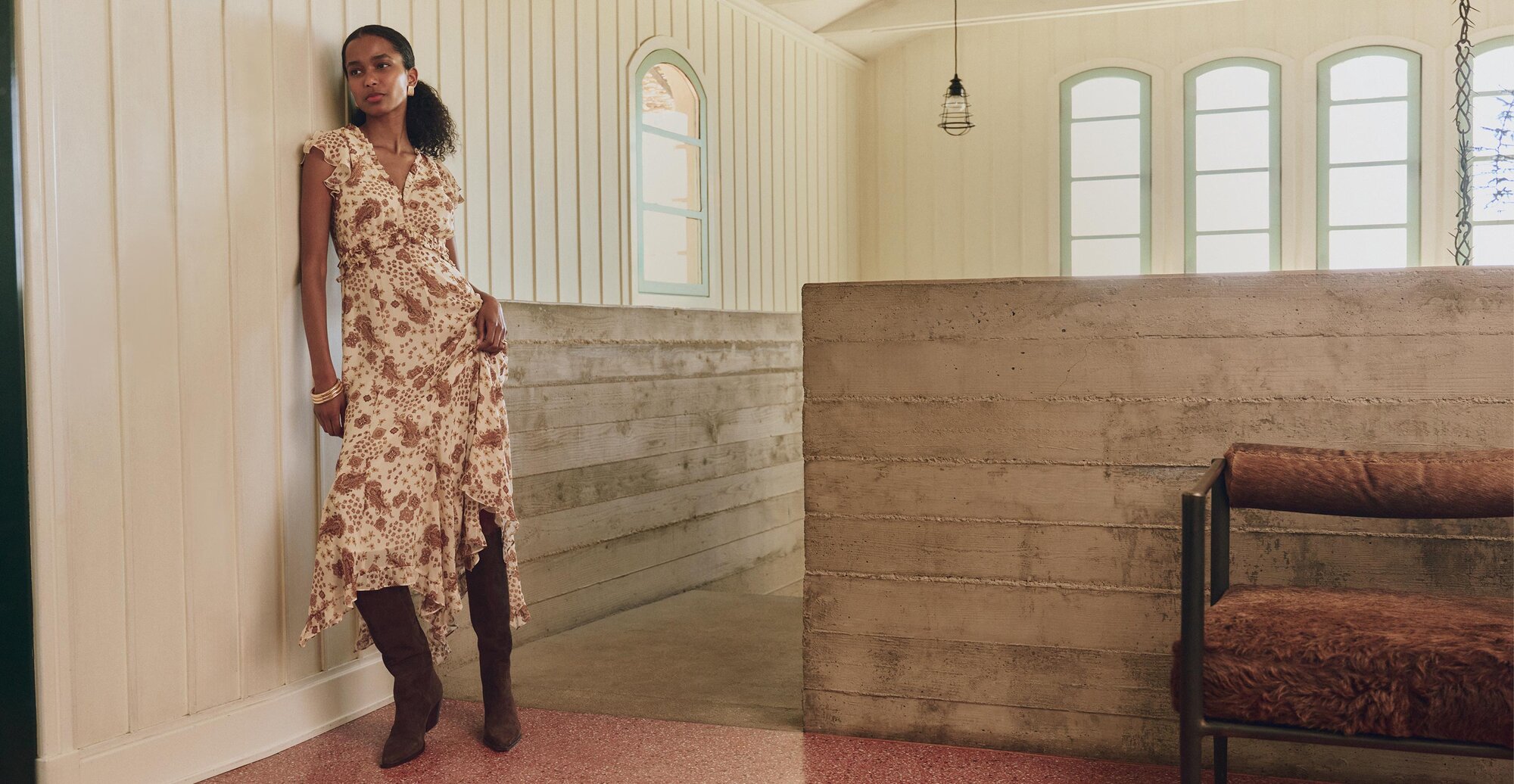 Woman wearing a cream and brown paisley printed mini dress and tall brown suede boots