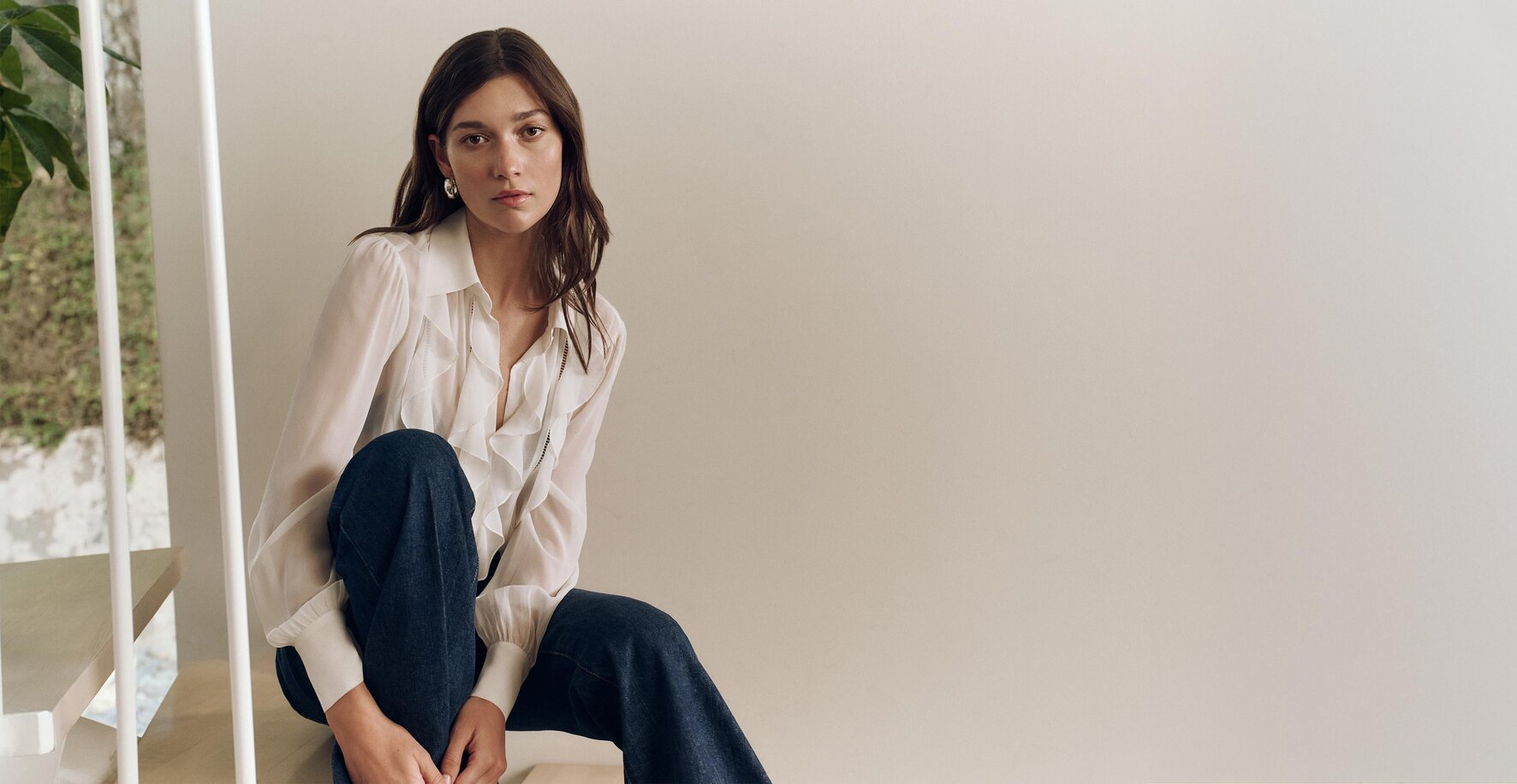 Woman wearing a white ruffle blouse and dark wash jeans