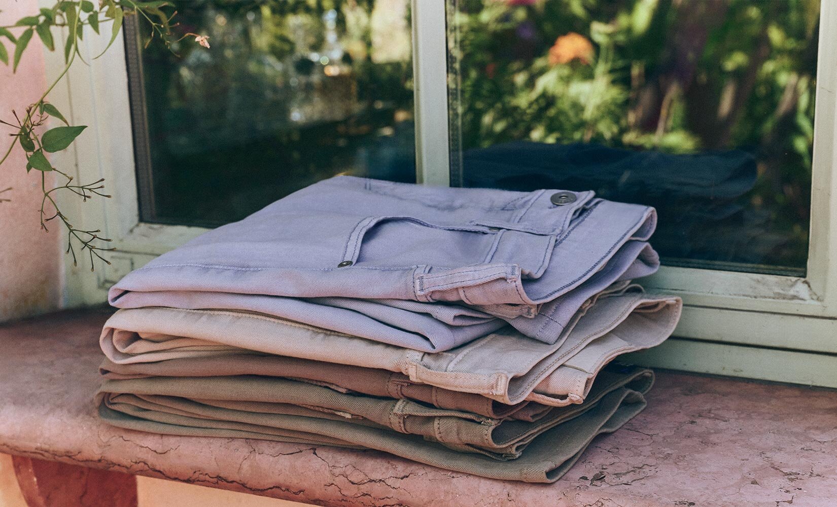 Product stack of blue, beige, brown, and green denim