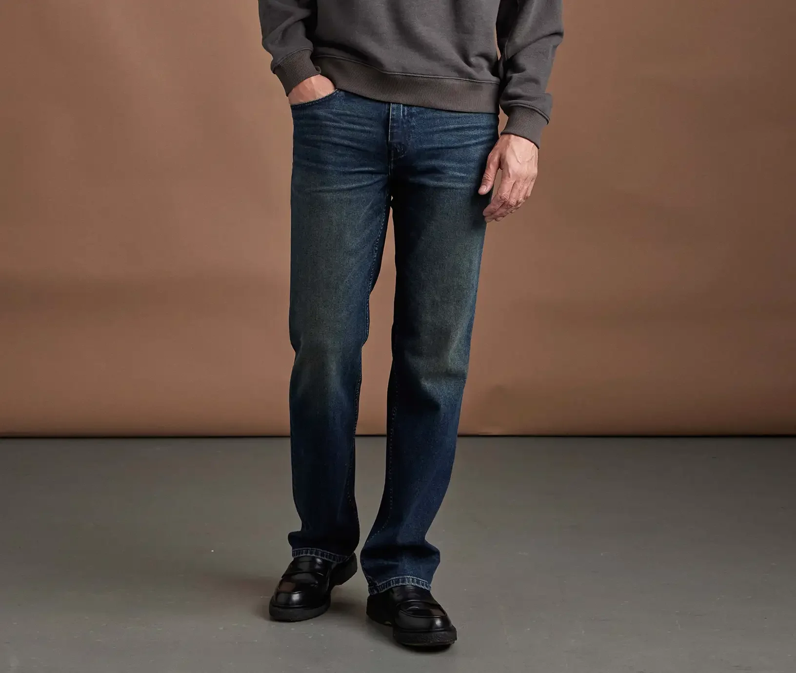 Man standing wearing relaxed dark wash jeans