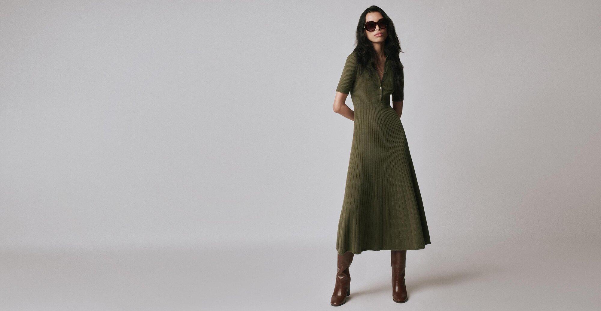Woman wearing an olive green knit midi dress with tall auburn boots