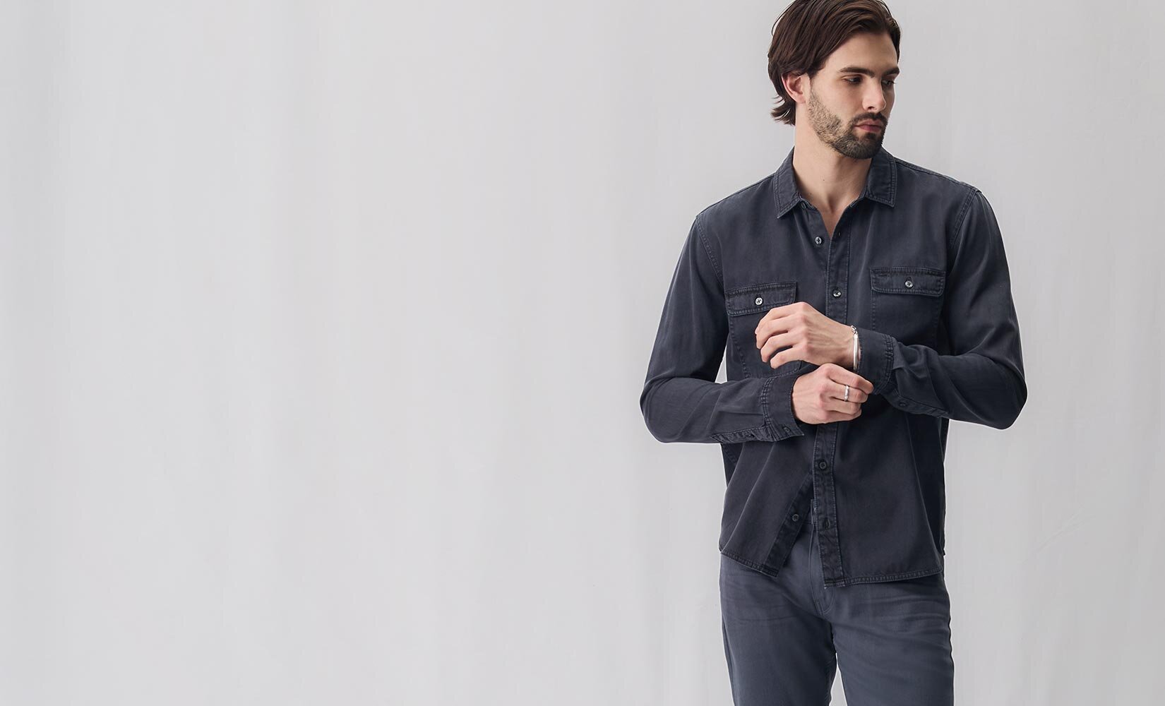 Man wearing a long sleeve navy blue button up shirt and pewter stone jeans