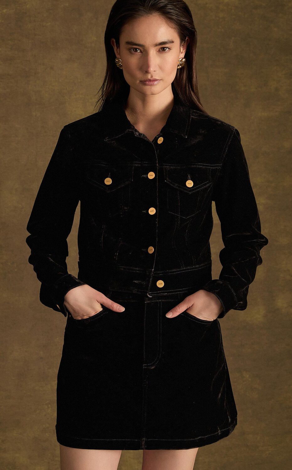 Woman wearing a matching black velvet denim jacket and mini skirt set