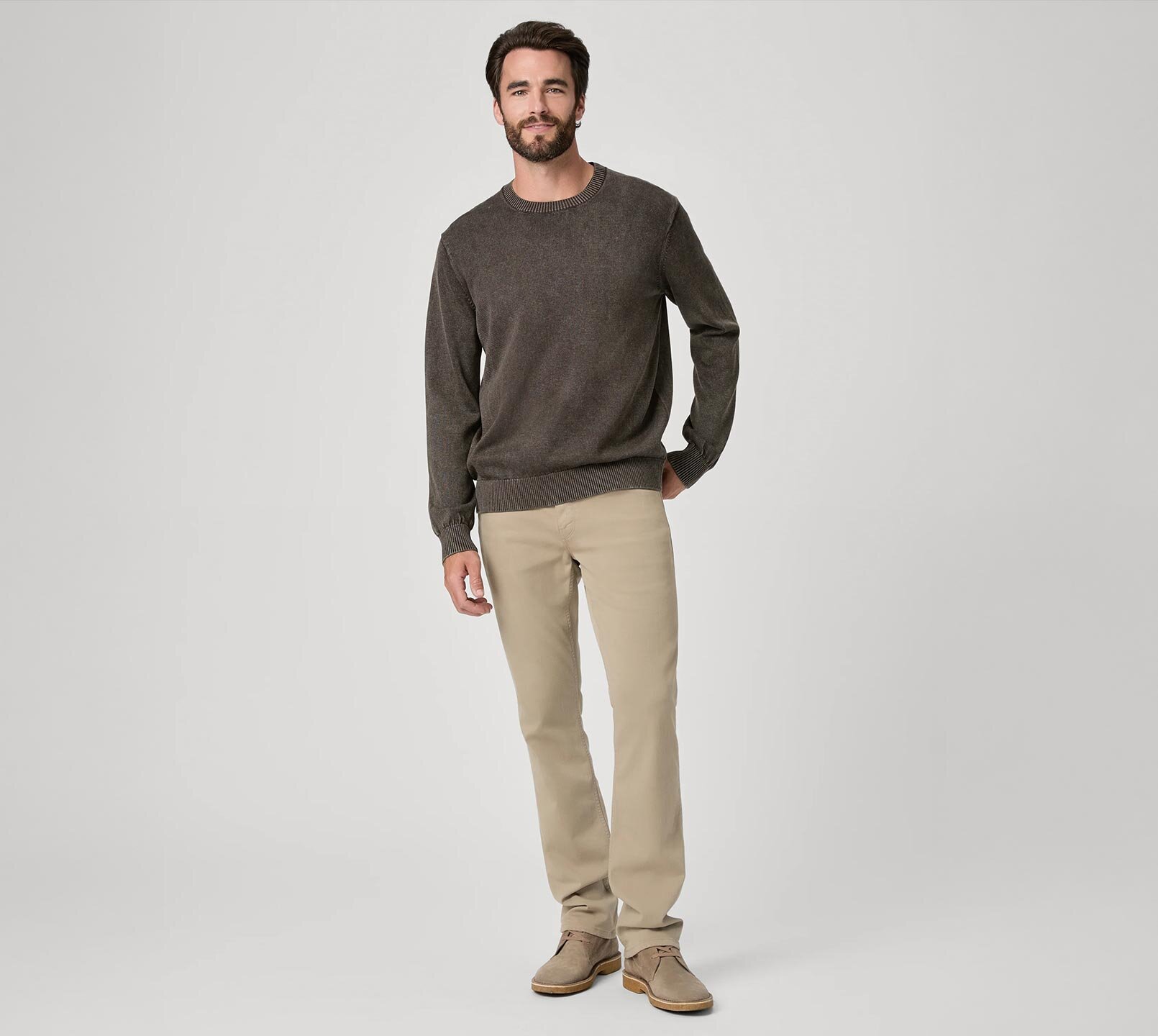 Man wearing a brown crewneck sweater, light brown straight leg jeans and taupe boots