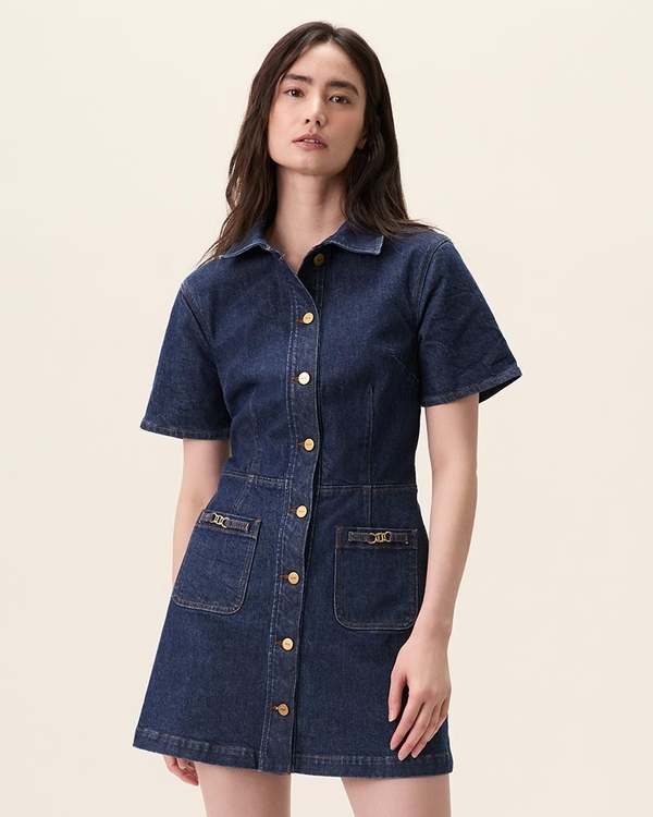 Woman wearing a short sleeve dark wash denim mini dress with gold buttons