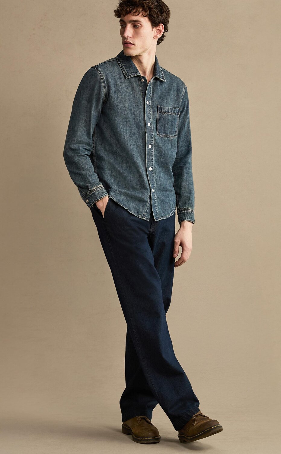 Man wearing a denim button up shirt, denim trousers, and brown boots
