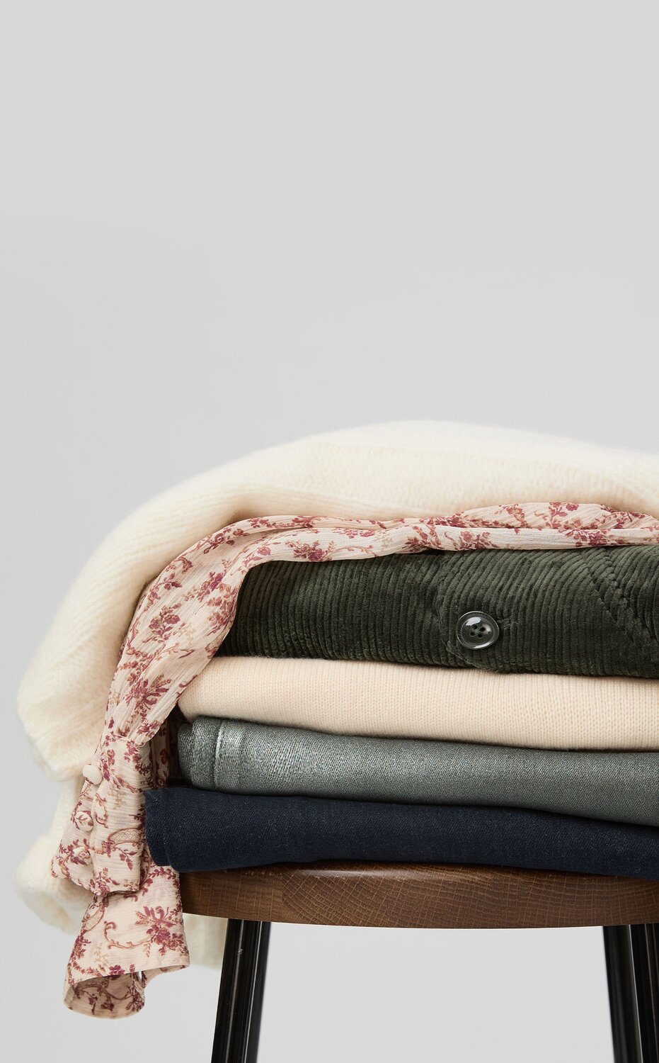 Stack of sweaters, tops and jeans on a stool