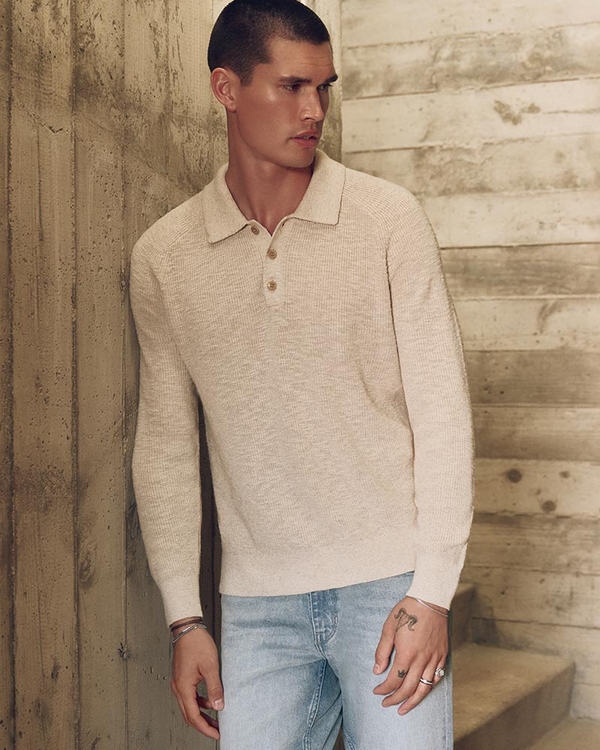 Man wearing a cream long sleeve sweater polo shirt and light wash jeans