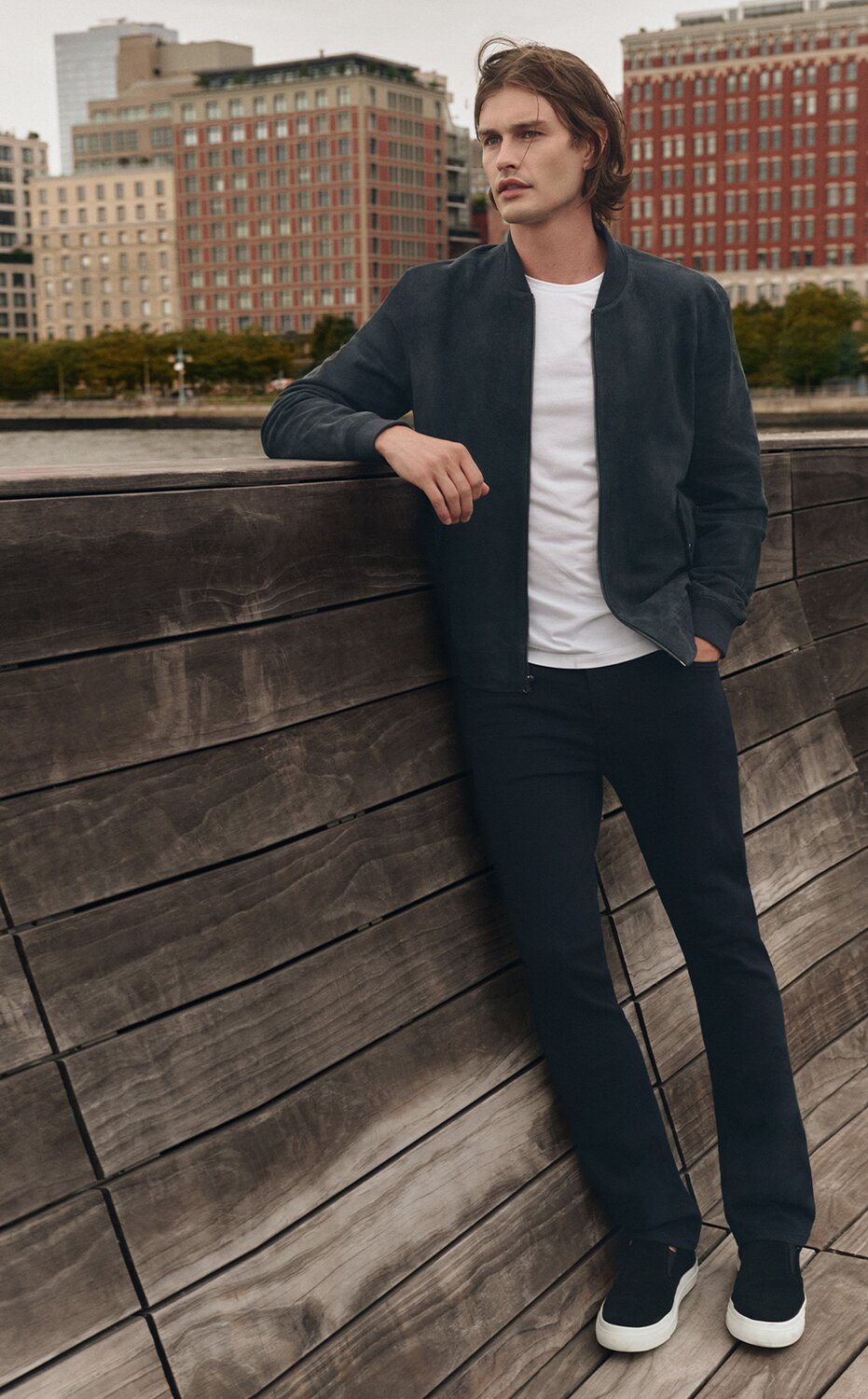 Man wearing a navy blue suede bomber jacket, a white t-shirt, and navy blue jeans