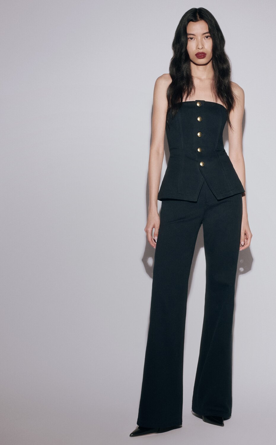 Woman sitting on a couch wearing a long brown sparkle dress with a brown cardigan and tall brown boots