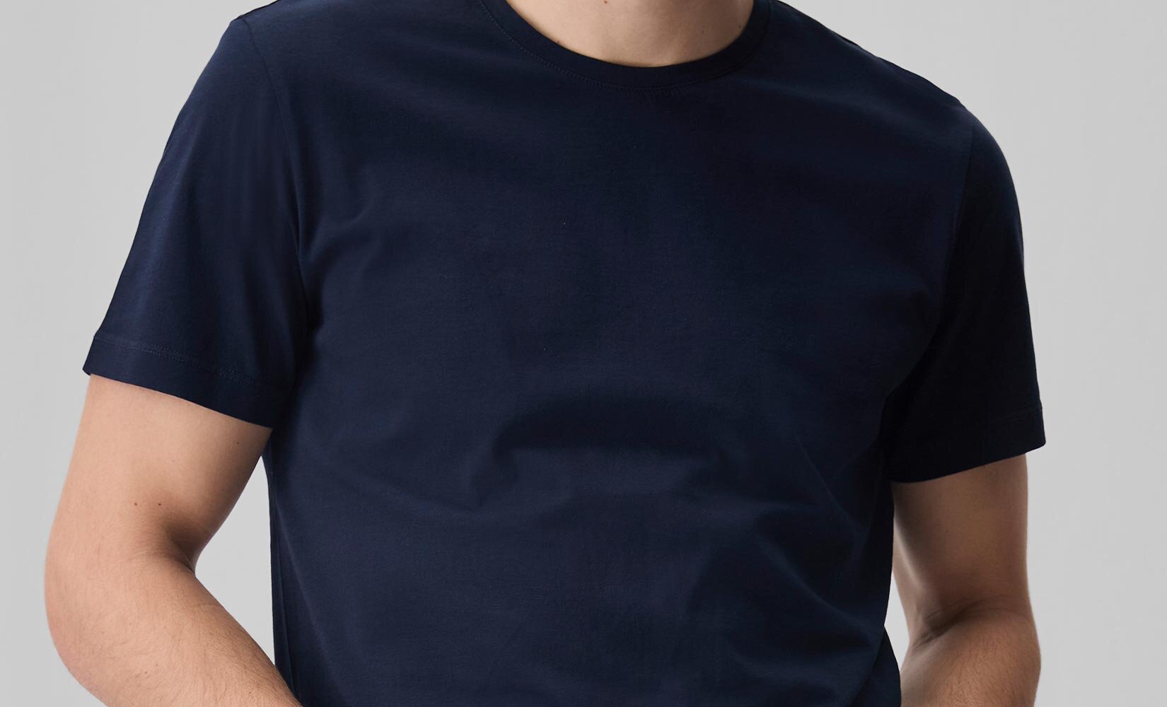 Man wearing a navy blue pima cotton short sleeve tee with light wash jeans