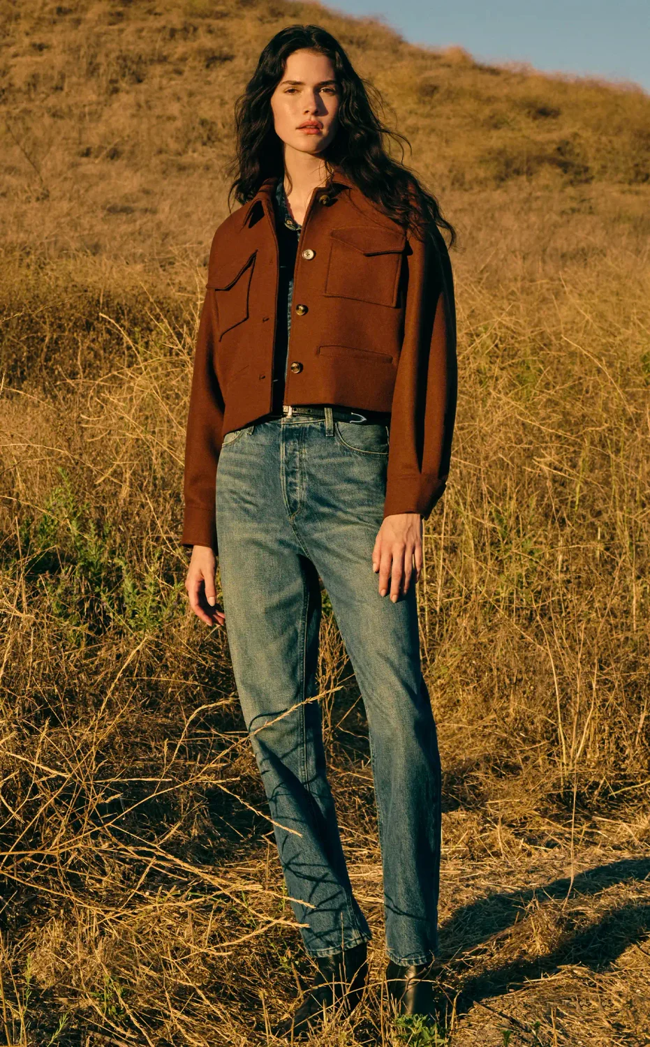 Woman twirling outside in a field wearing a textured silk long sleeve mini dress in a brown striped tapestry print