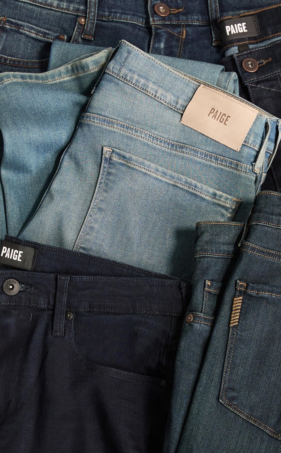 A collection of PAIGE denim jeans in an array of washes from light to dark