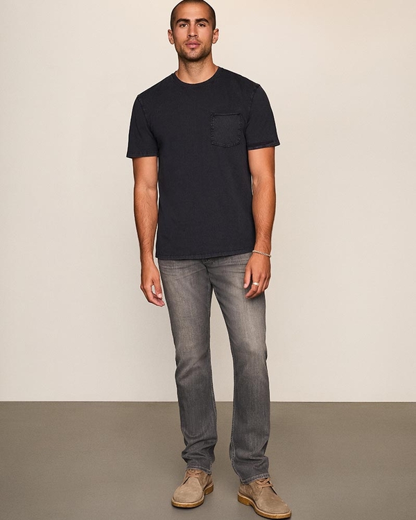 Man wearing a black short sleeve tee, grey wash jeans, and taupe boots