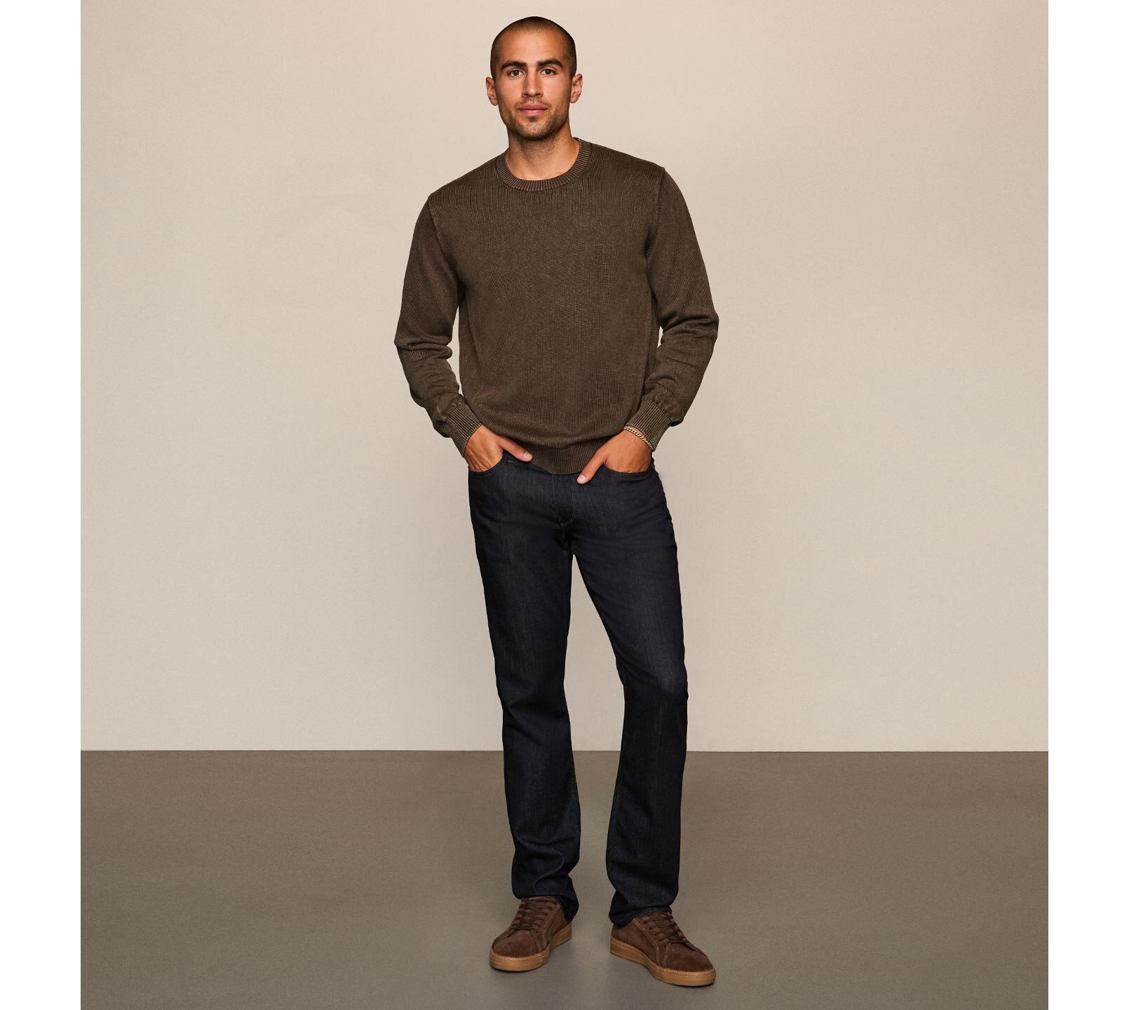 Man wearing a brown sweater with dark wash jeans and brown sneakers
