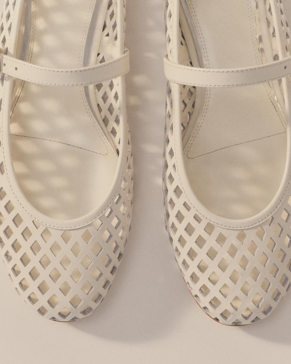 White perforated Mary Jane flats with cutout detailing, shown from above.