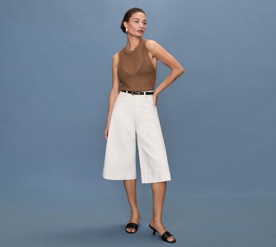 Woman wearing a brown open knit tank, ecru gaucho jeans, black belt & black heel mule sandals