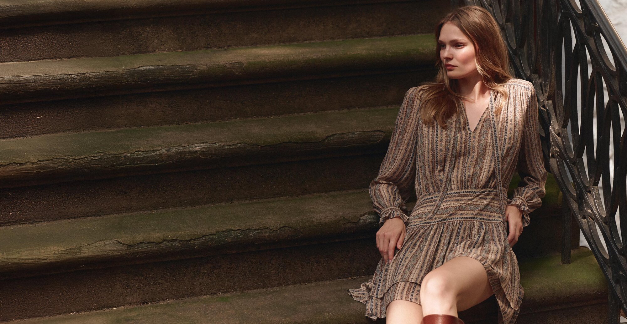 Woman wearing a brown tapestry striped silk long sleeve mini dress and tall auburn boots