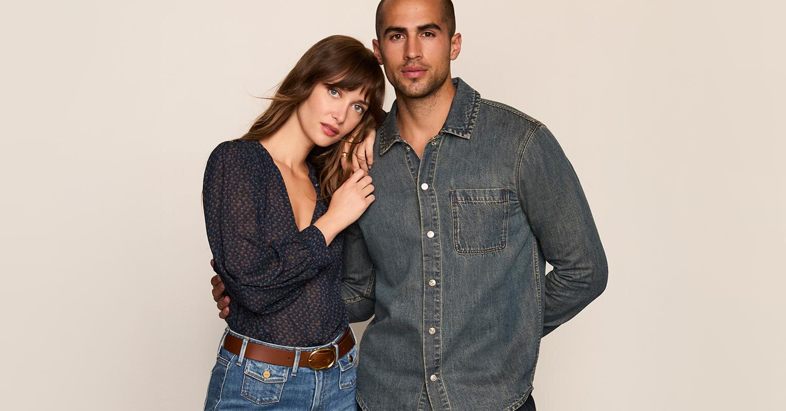 Woman wearing a blue blouse with light wash jeans and a brown belt. Man wearing a dark wash denim shirt.