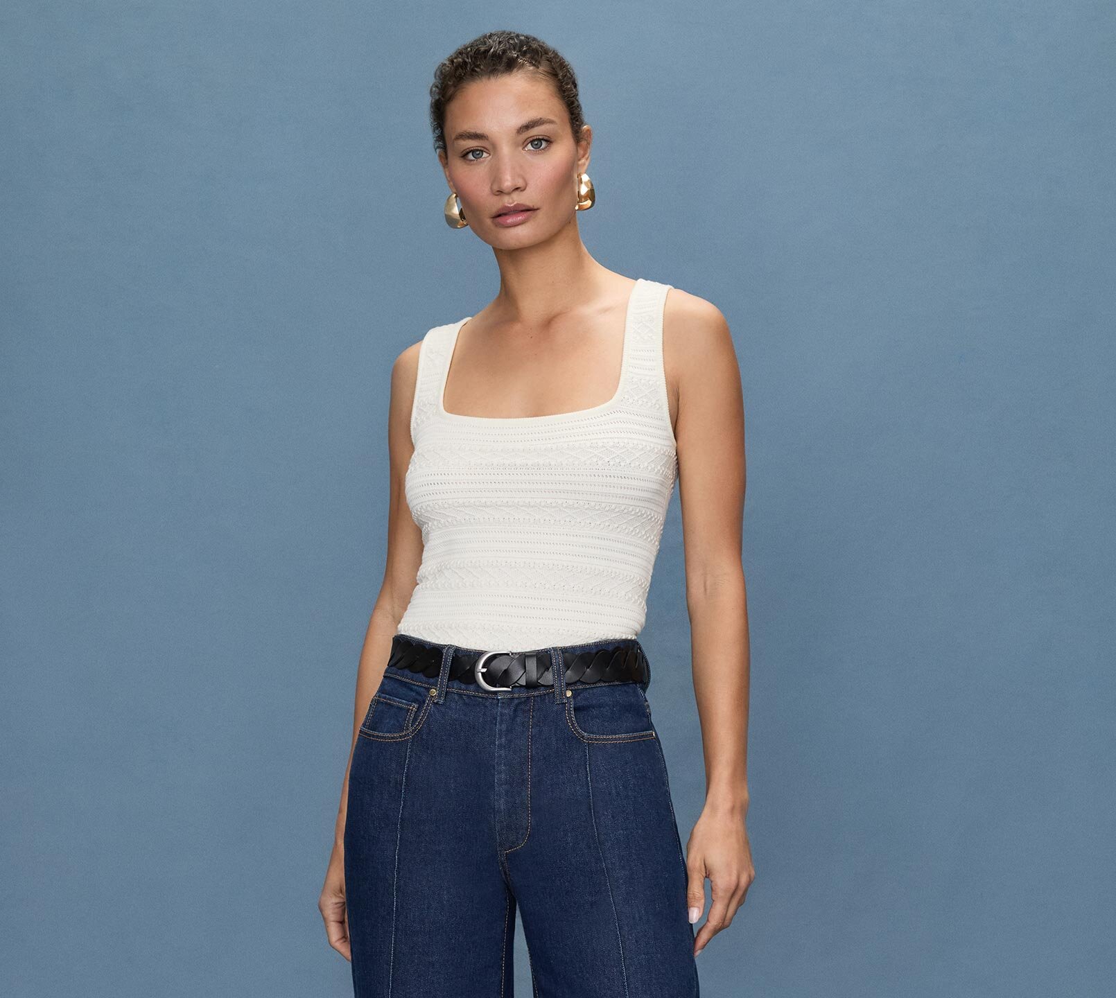 Woman standing a light blue quilted jacket, white tee, medium wash jeans and bone ankle boots