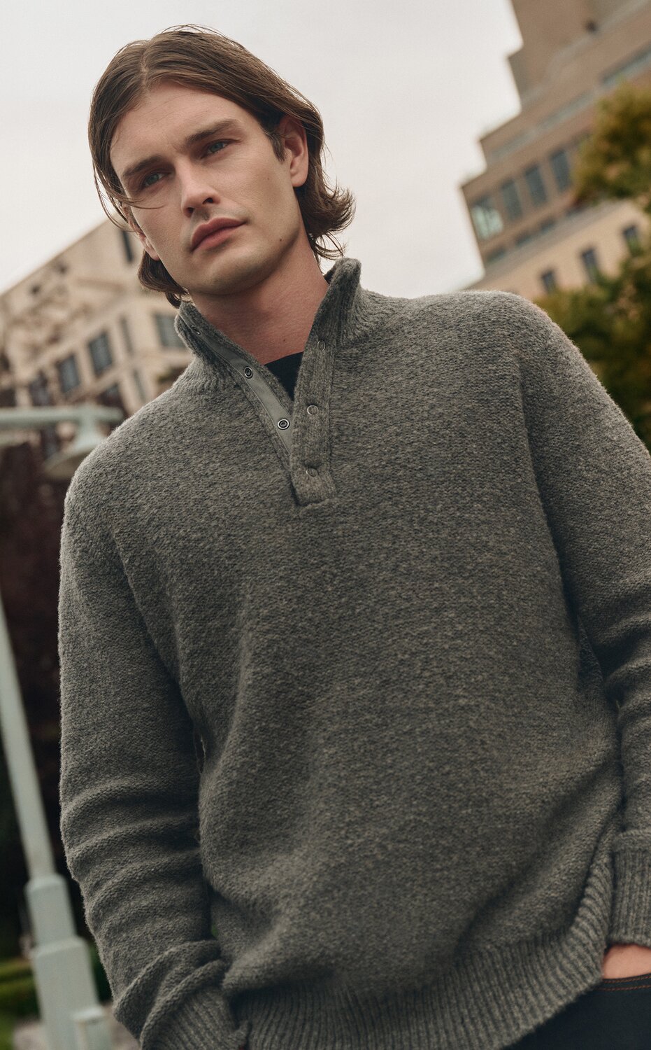 Man wearing a navy blue suede bomber jacket, a white t-shirt, and navy blue jeans