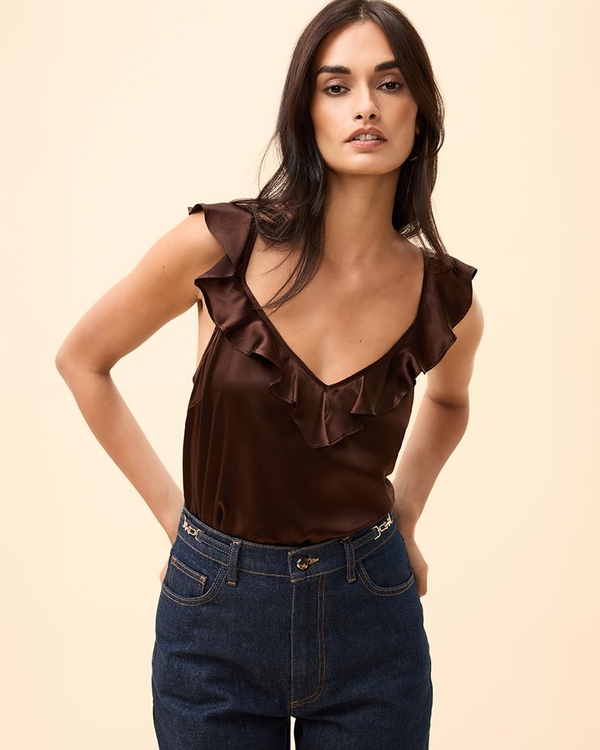Woman wearing a brown ruffle cami tucked into dark wash jeans