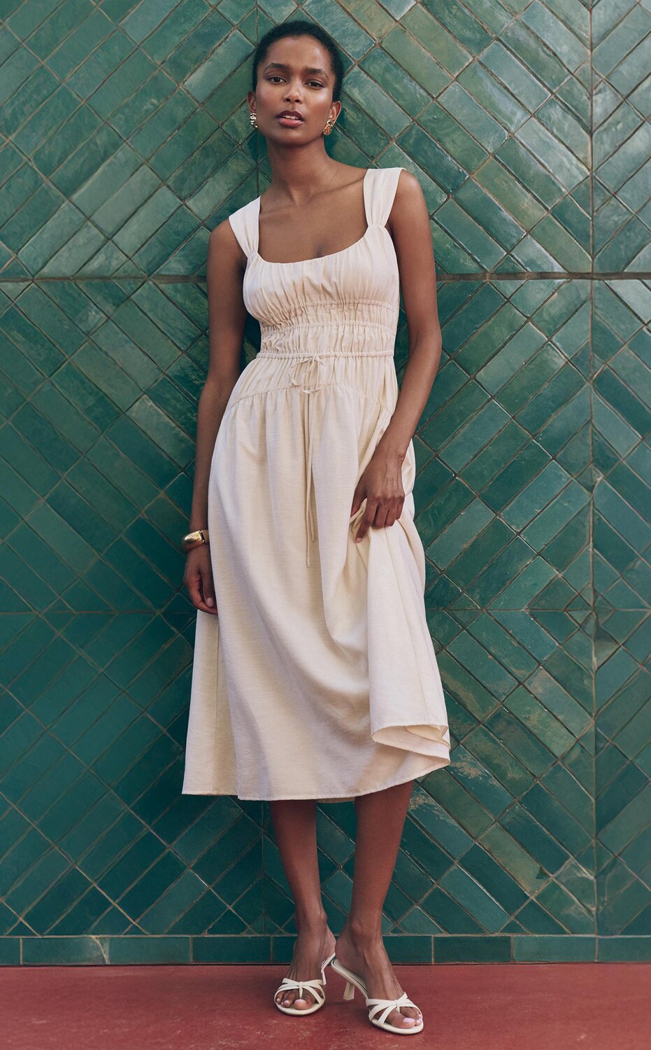 Woman wearing an oyster white flowy midi dress and ivory heeled sandals