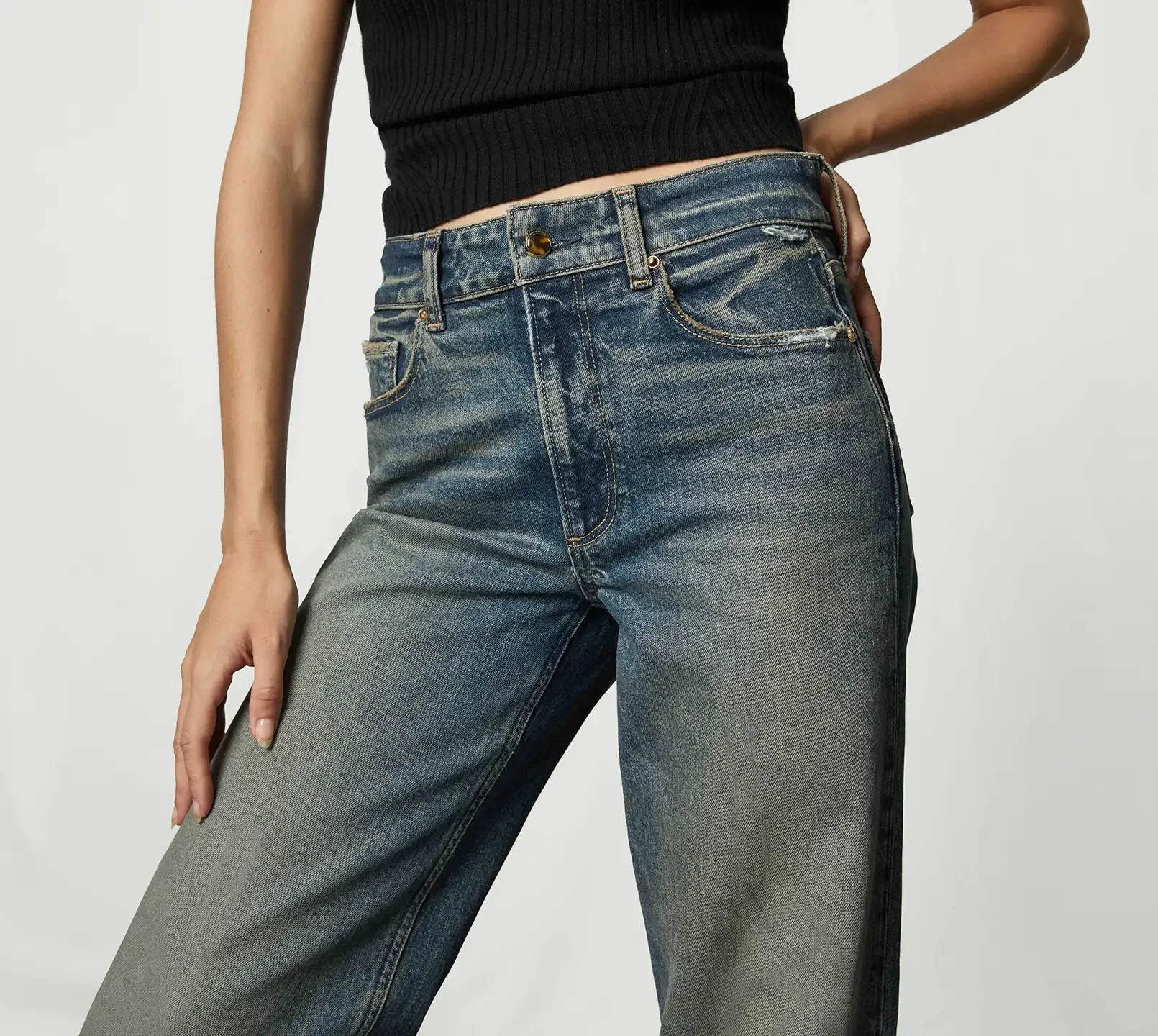 Woman standing wearing a black tank top and dark wash wide leg jeans