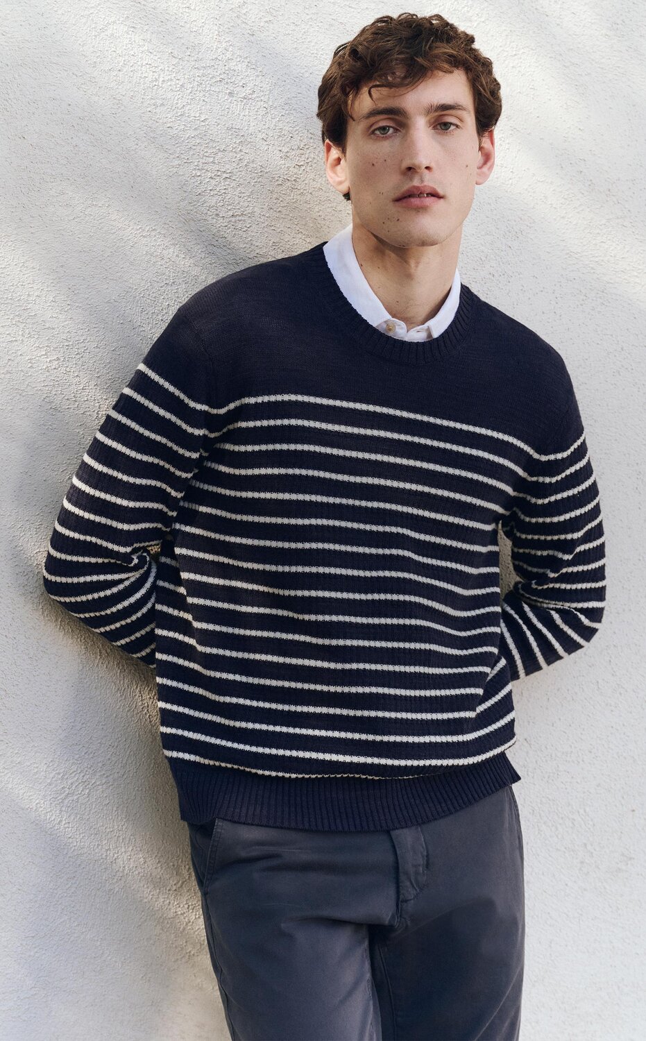 Man wearing a navy and white striped sweater and navy blue pants