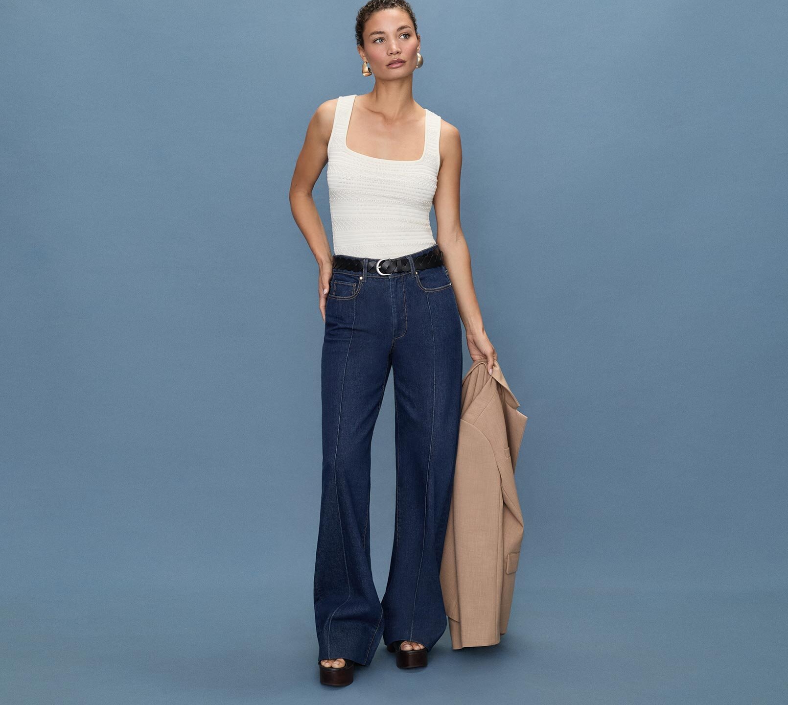 Woman standing a light blue quilted jacket, white tee, medium wash jeans and bone ankle boots