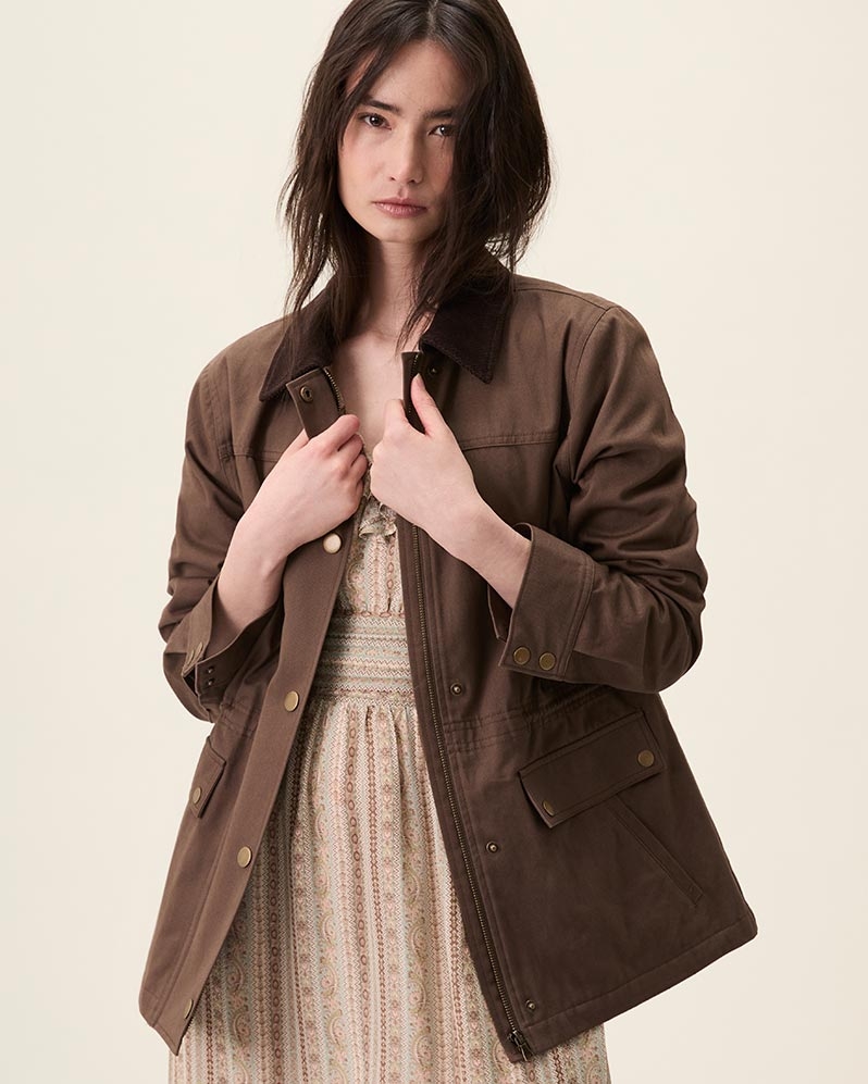 Woman wearing a brown jacket over a brown tapestry striped silk midi dress