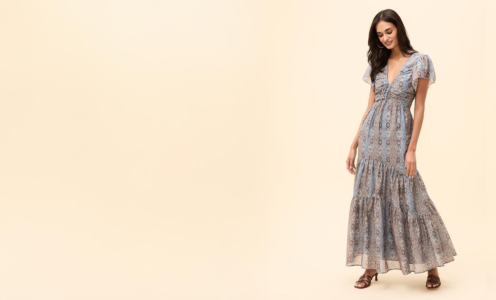Woman wearing a long slate blue printed dress and brown sandals