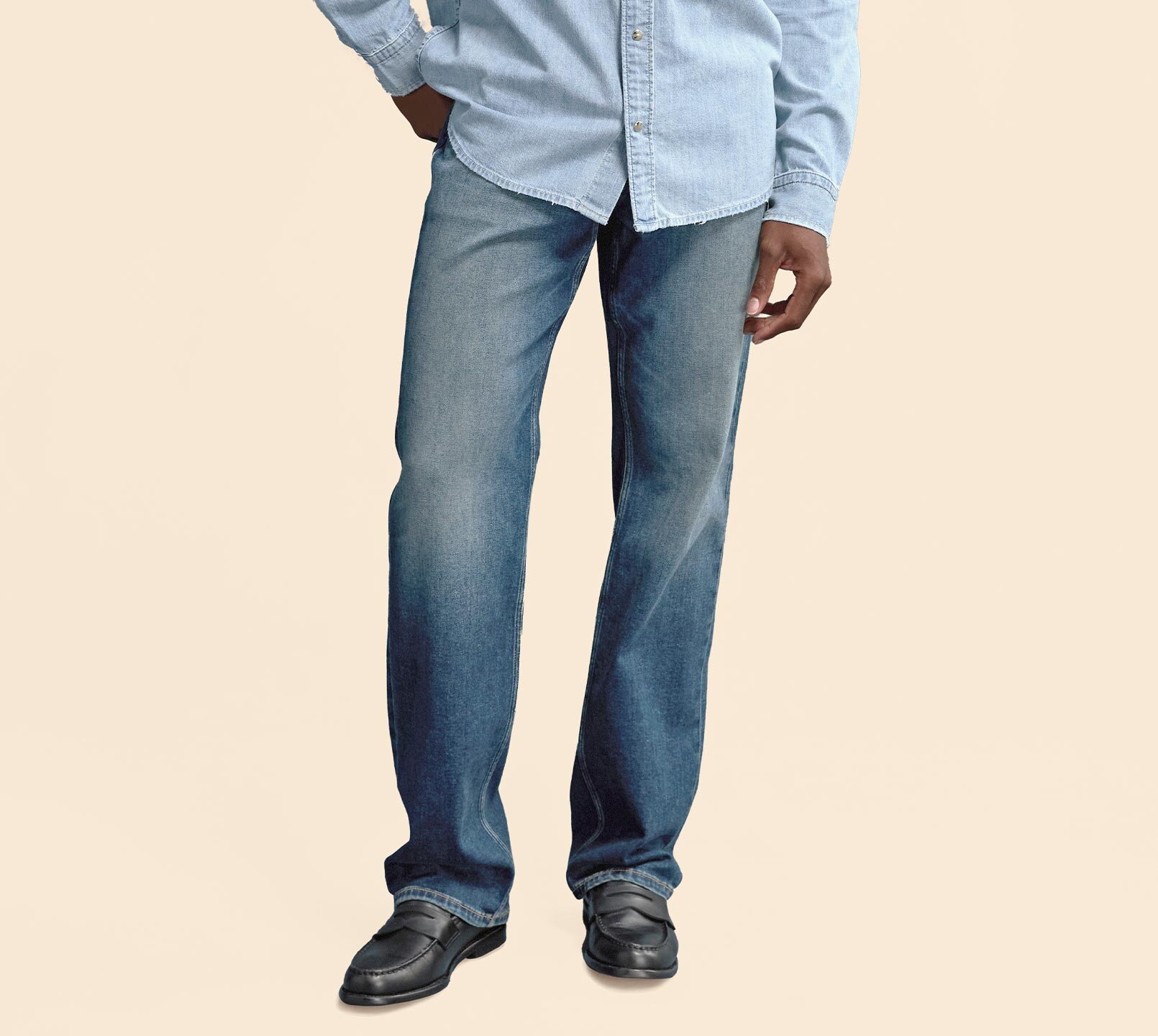 Man wearing a light wash long sleeve denim button up shirt, dark wash relaxed fit jeans and black loafers