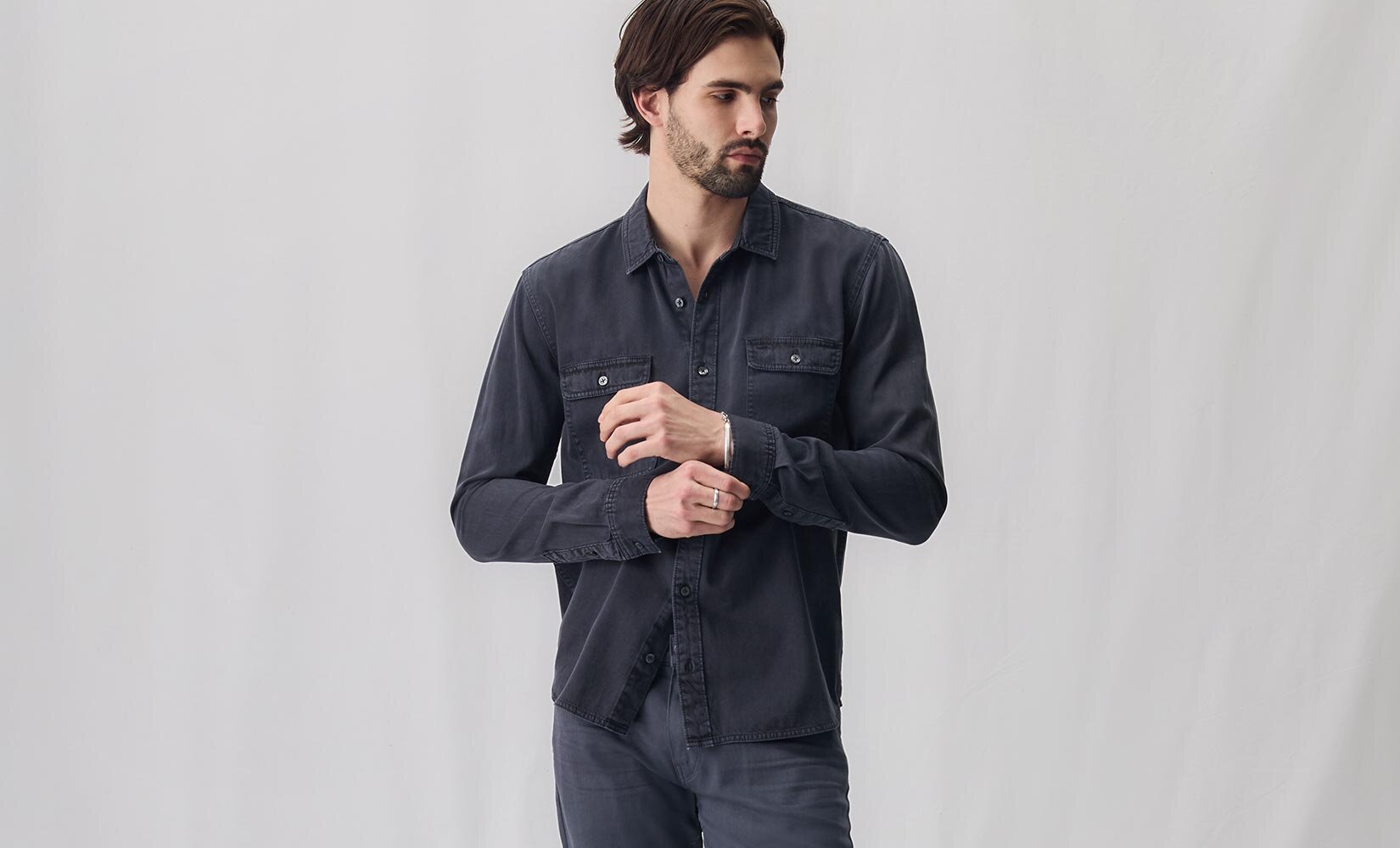 Man wearing a long sleeve navy blue button up shirt and pewter stone jeans
