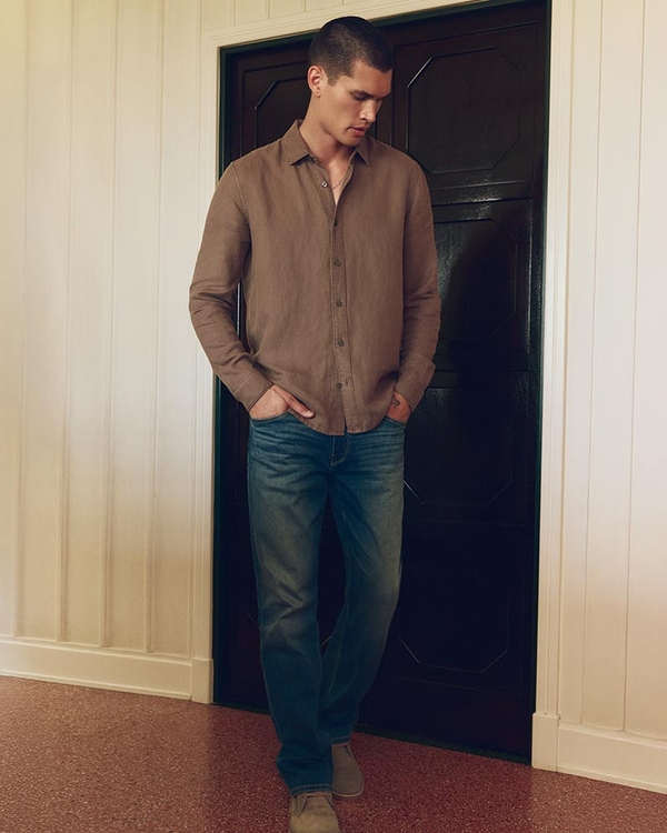 Man wearing a brown long sleeve shirt, dark wash relaxed straight leg jeans and slate boots