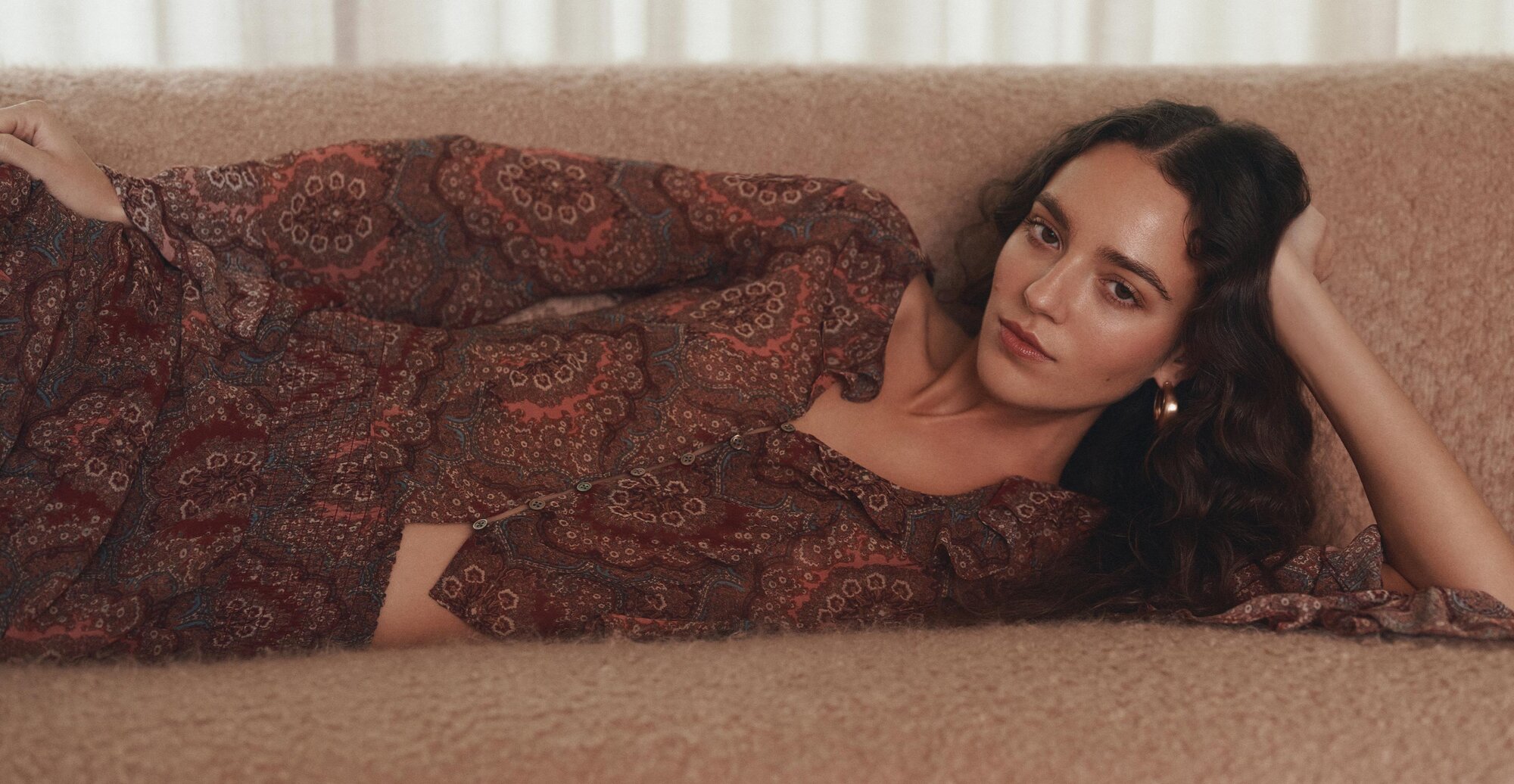 A woman laying on a sofa wearing a red paisley printed silk blouse with a matching red paisley printed silk skirt
