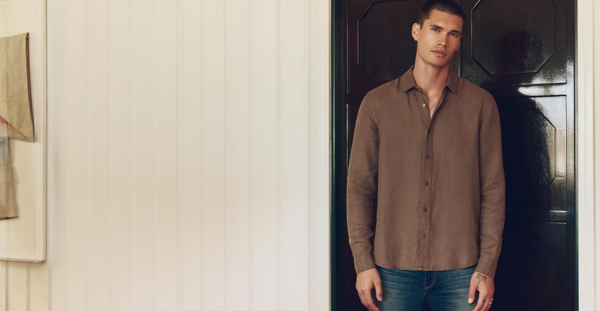 Man wearing a brown long sleeve button up shirt and dark wash jeans