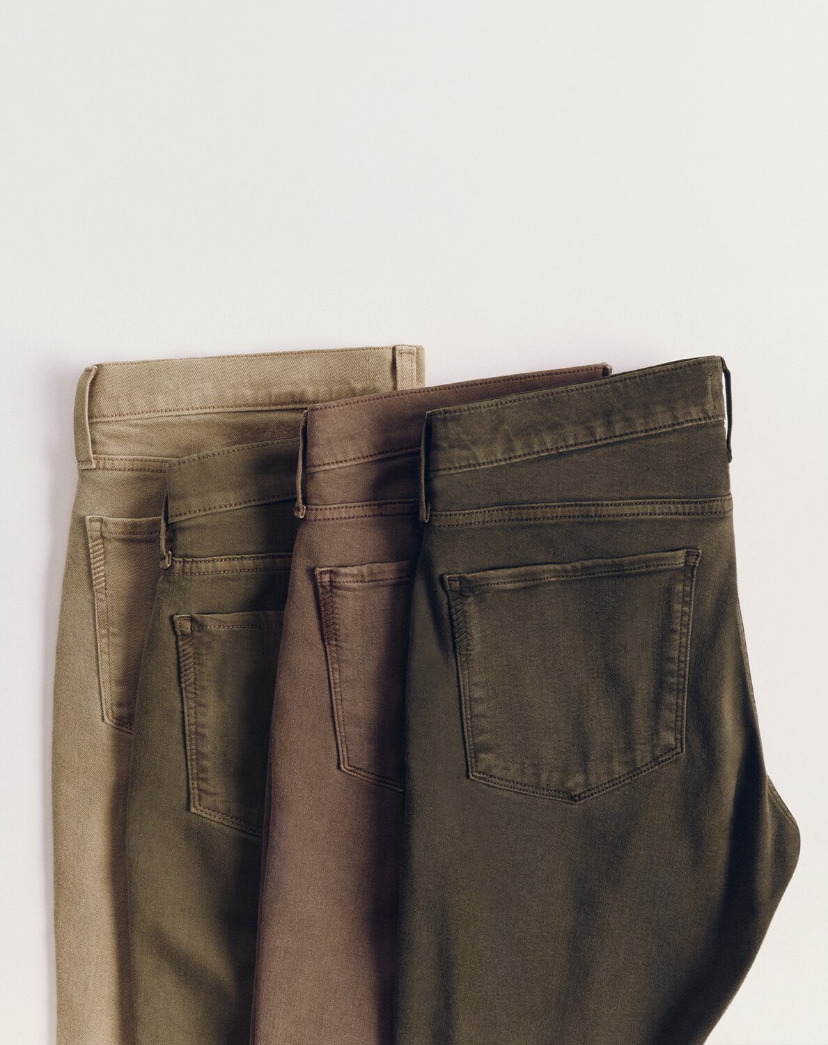 Close-up of folded PAIGE men's denim in rich, earthy neutral shades from the TRANSCEND COLOR collection.