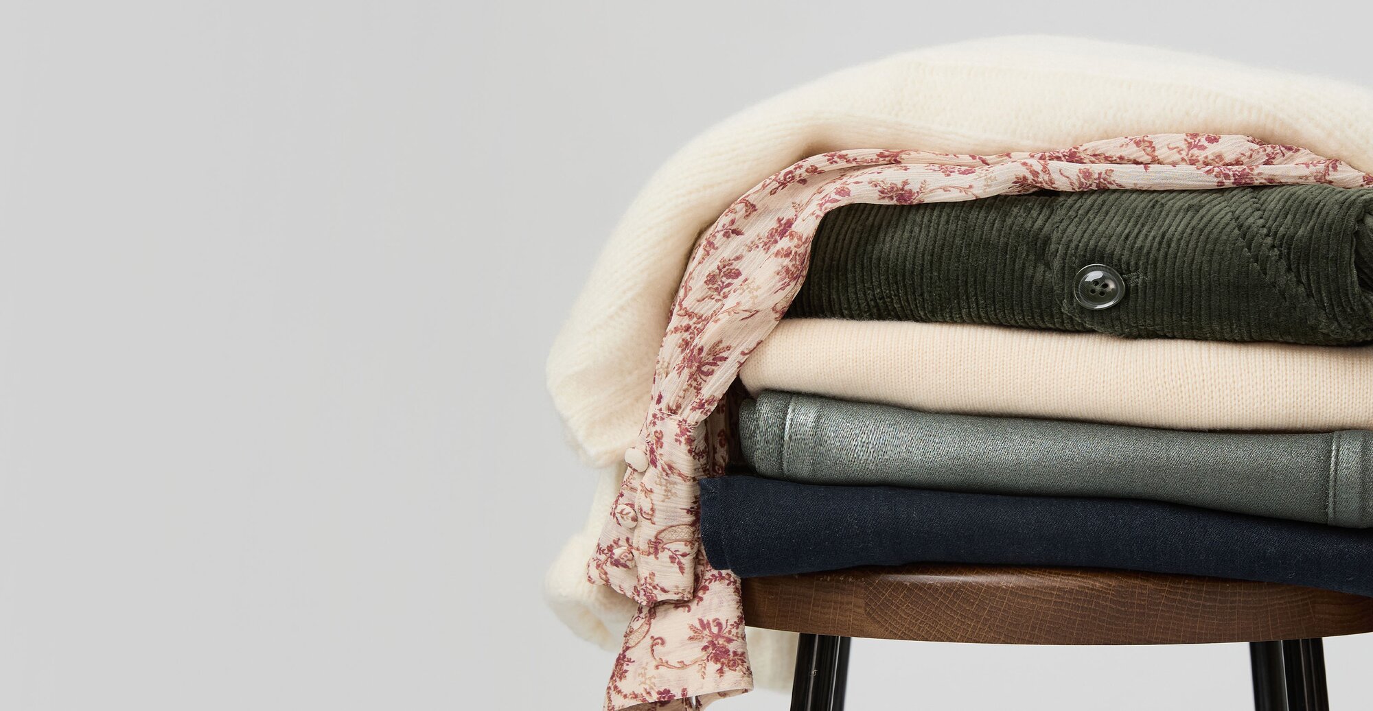 Stack of sweaters, tops and jeans on a stool