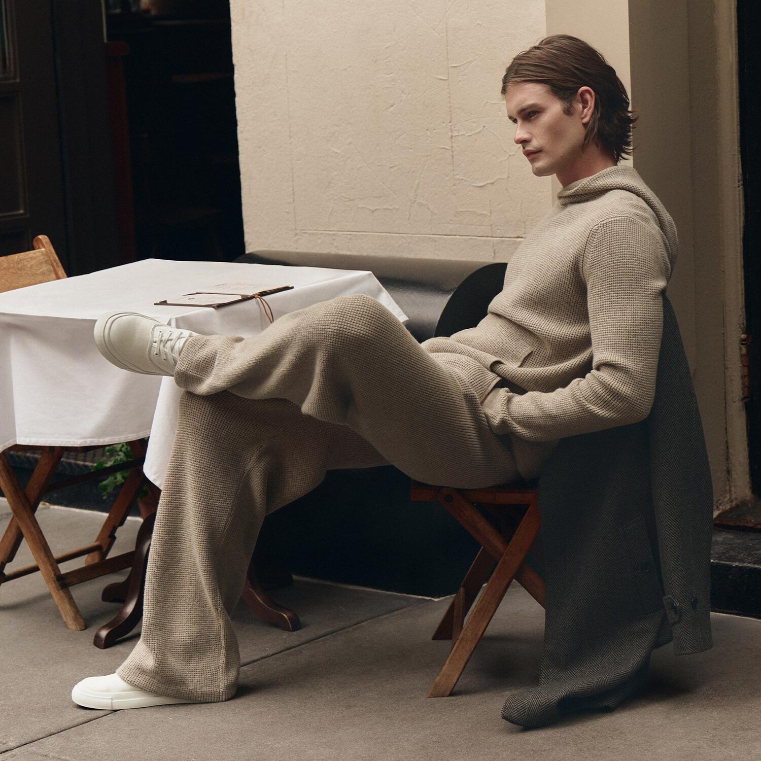 Man wearing a beige sweater knit hoodie and pant set with white sneakers