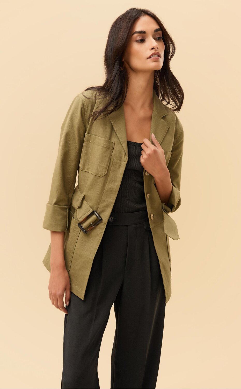 Woman wearing an army green jacket, black tank top and black pants, woman wearing a dark wash denim dress