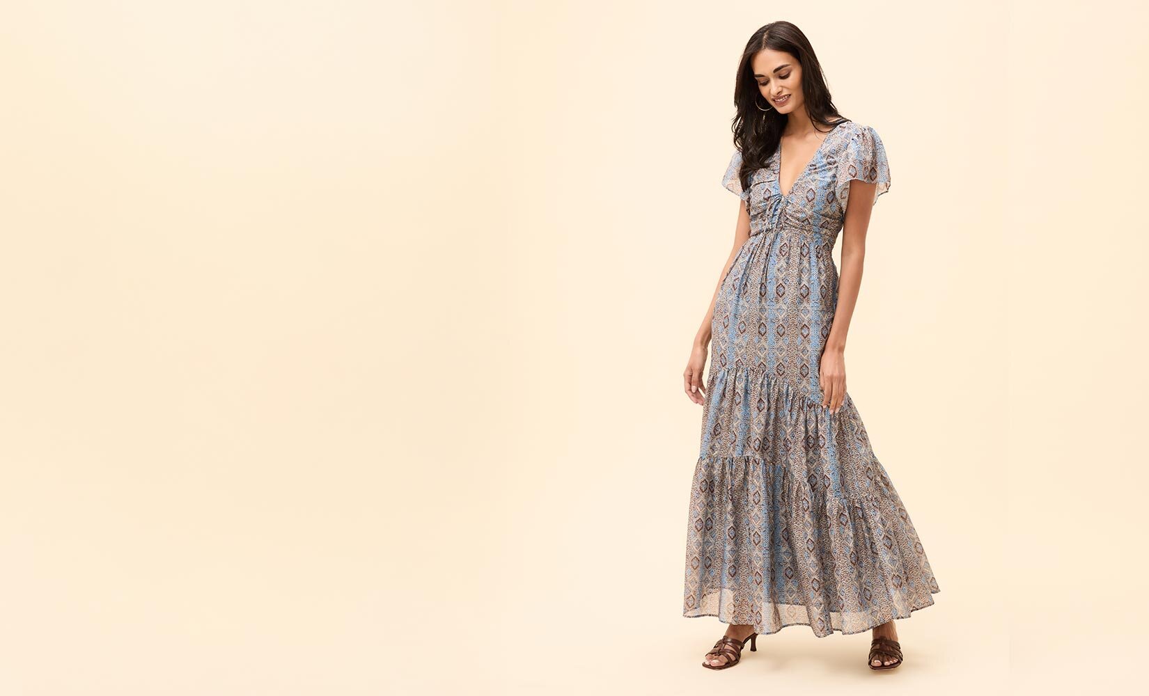 Woman wearing a long slate blue printed dress and brown sandals