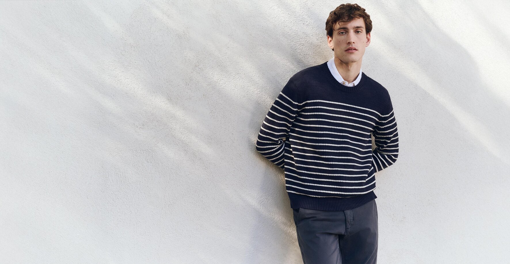 Man wearing a navy and white striped sweater and navy blue pants