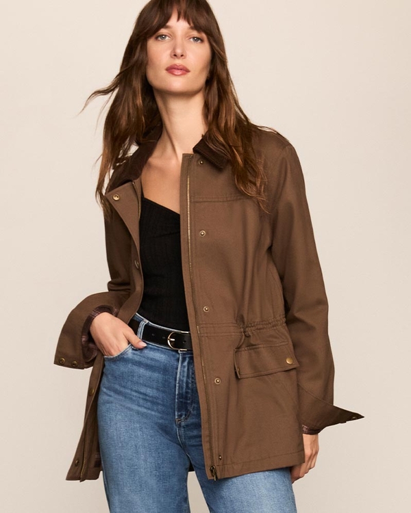 Woman wearing a brown jacket over a black top with a black belt and wide leg jeans