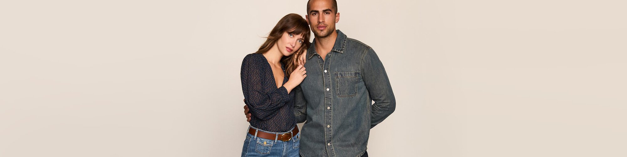 Woman wearing a blue blouse with light wash jeans and a brown belt. Man wearing a dark wash denim shirt.
