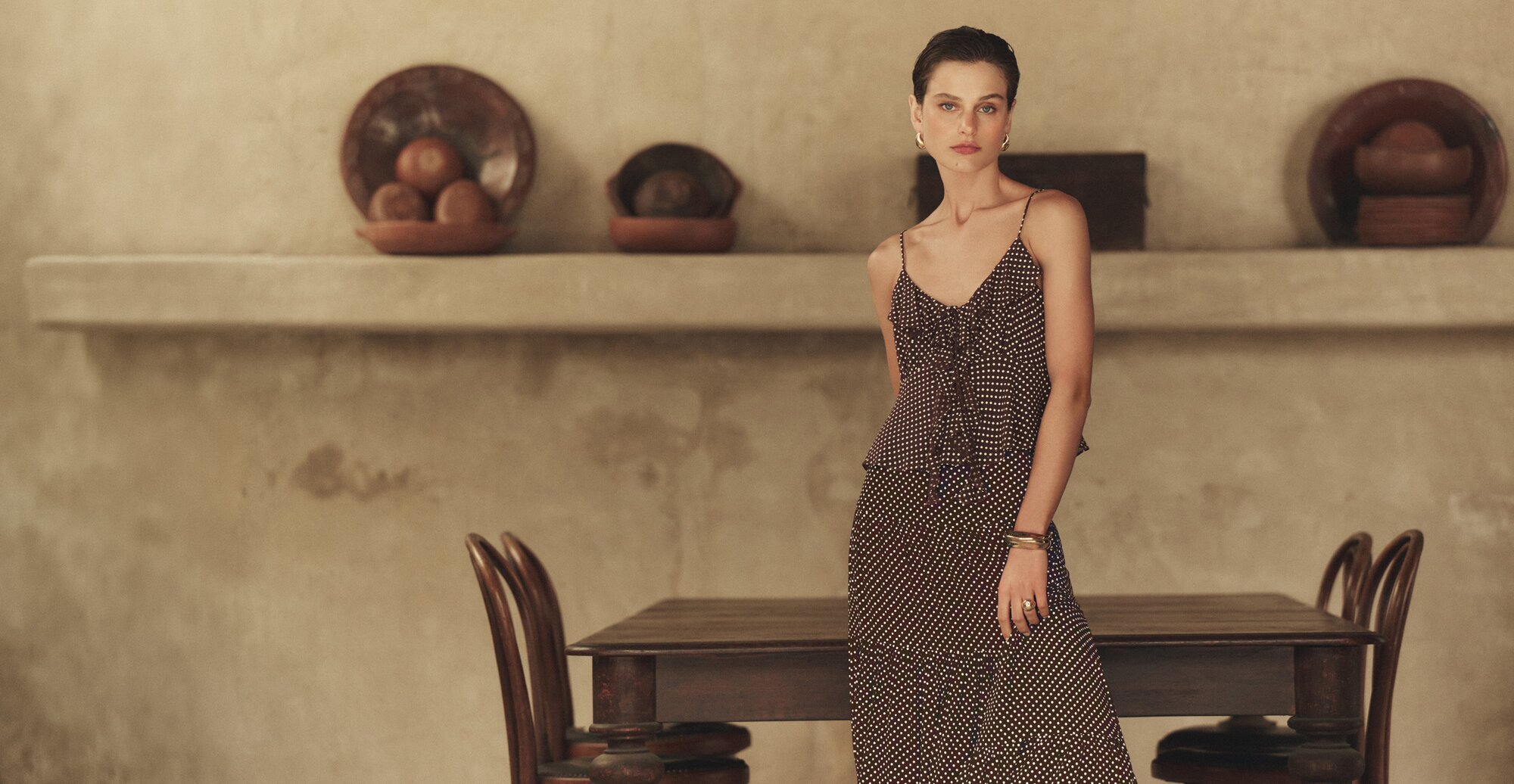 Woman wearing a white and brown polka dot ruffle cami blouse with a maxi skirt in a matching print.