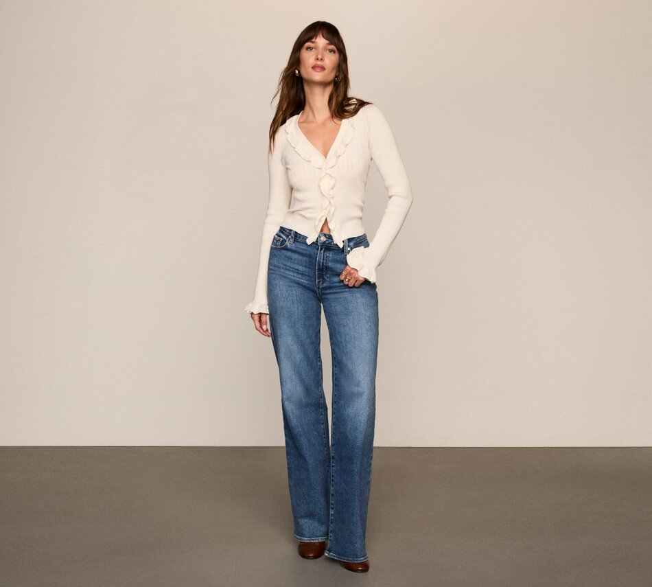 Woman wearing a white cardigan with medium wash jeans and brown boots